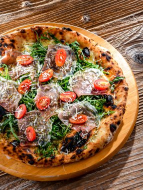 Pizza Italiana jambon, peynir, domates ve roka ile servis edilir..