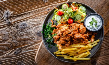 Kebab served with french fries, vegetable salad and tzatziki