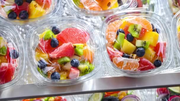 市販の冷蔵庫で販売のために置く パッケージ化されたフルーツサラダ付きのプラスチックボックス — ストック動画