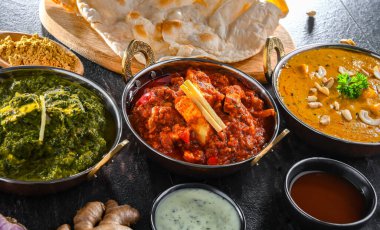 Hint yemekleri ile kompozisyon: medras paneer, palak paneer ve shahi paneer ile orijinal Hint karahi kaplarında servis edilen basmati pilavı.