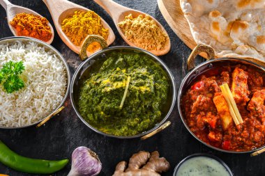 Hint yemekleri ile kompozisyon: medras paneer, palak paneer ve shahi paneer ile orijinal Hint karahi kaplarında servis edilen basmati pilavı.