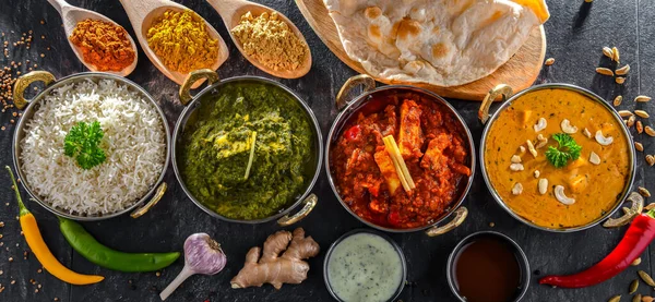 stock image Composition with indian dishes: madras paneer, palak paneer and shahi paneer with basmati rice served in original indian karahi pots.