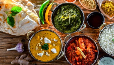 Composition with indian dishes: madras paneer, palak paneer and shahi paneer with basmati rice served in original indian karahi pots. clipart
