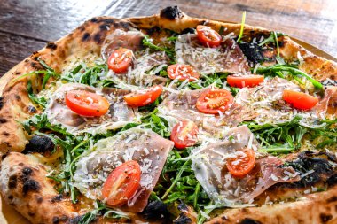 Pizza Italiana jambon, peynir, domates ve roka ile servis edilir..