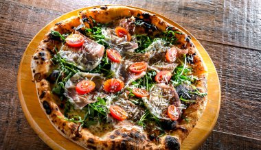 Pizza Italiana jambon, peynir, domates ve roka ile servis edilir..