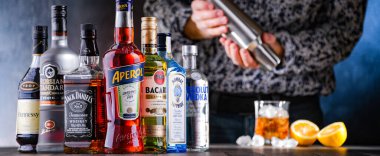 POZNAN, POL - 28 DEC 2021: Çeşitli küresel likör markaları ve kokteyl karıştırıcıyla içki hazırlayan bir barmen