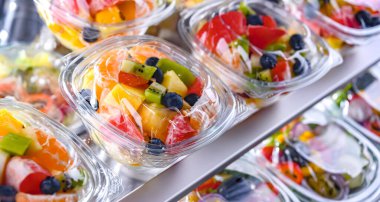 Plastic boxes with pre-packaged fruit salads, put up for sale in a commercial refrigerator