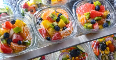Plastic boxes with pre-packaged fruit salads, put up for sale in a commercial refrigerator