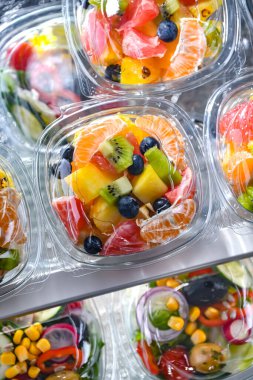 Plastic boxes with pre-packaged fruit salads, put up for sale in a commercial refrigerator