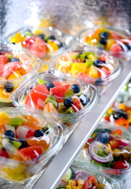 Plastic boxes with pre-packaged fruit salads, put up for sale in a commercial refrigerator