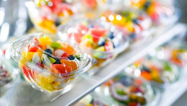Plastic boxes with pre-packaged fruit salads, put up for sale in a commercial refrigerator