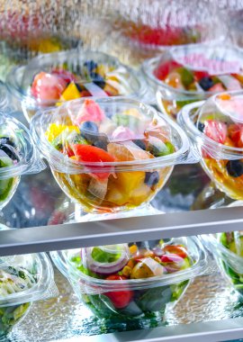 Plastic boxes with pre-packaged fruit salads, put up for sale in a commercial refrigerator