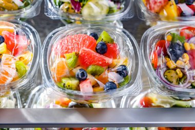 Plastic boxes with pre-packaged fruit salads, put up for sale in a commercial refrigerator