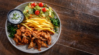 Kebab served with french fries, vegetable salad and tzatziki