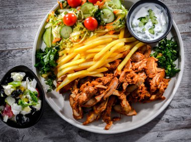 Kebab served with french fries, vegetable salad and tzatziki