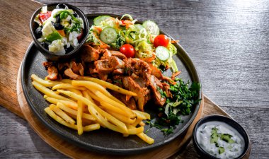 Kebab served with french fries, vegetable salad and tzatziki