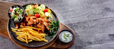 Kebab served with french fries, vegetable salad and tzatziki