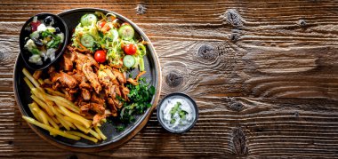 Kebab served with french fries, vegetable salad and tzatziki