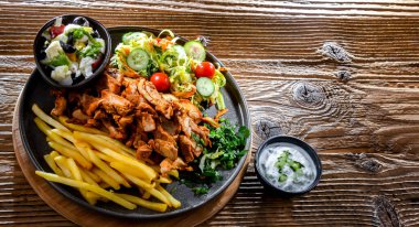 Kebab served with french fries, vegetable salad and tzatziki