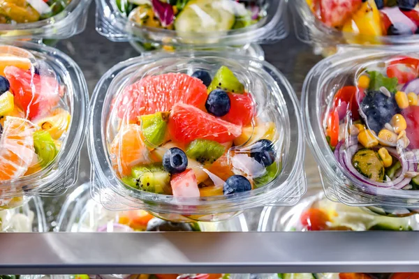 市販の冷蔵庫で販売のために置く パッケージ化されたフルーツサラダ付きのプラスチックボックス — ストック写真