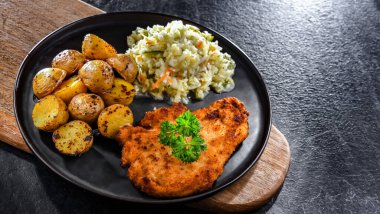 Patates ve lahana ile servis edilen ekmek kırıntılarıyla kaplı tavuk pirzolası.