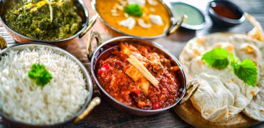 Composition with indian dishes: madras paneer, palak paneer and shahi paneer with basmati rice served in original indian karahi pots clipart