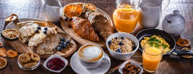 Breakfast served with coffee, orange juice, scrambled eggs, cereals, pancakes and croissants.