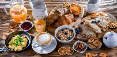 Breakfast served with coffee, orange juice, scrambled eggs, cereals, pancakes and croissants.
