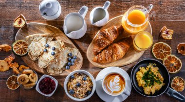 Breakfast served with coffee, orange juice, scrambled eggs, cereals, pancakes and croissants.