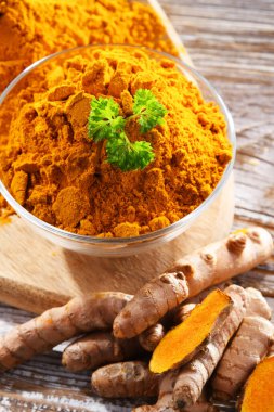 Bir kase zemin zerdeçal ve taze rhizomu ile kompozisyon.