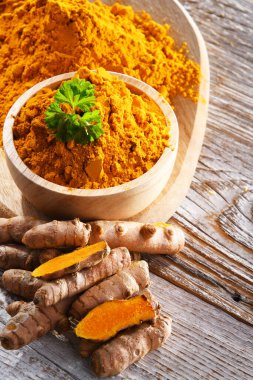 Bir kase zemin zerdeçal ve taze rhizomu ile kompozisyon.