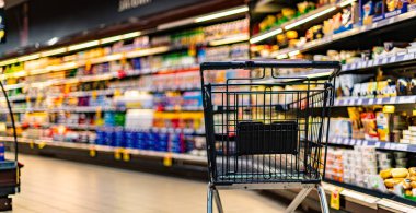 A shopping cart by a store shelf in a supermarket clipart