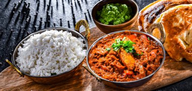 Pirinçli tereyağlı tavuk ve Hint karahi kaplarında servis edilen mısır ekmeği..