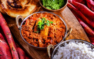 Butter chicken with rice and naan flatbread served in original indian karahi pots. clipart