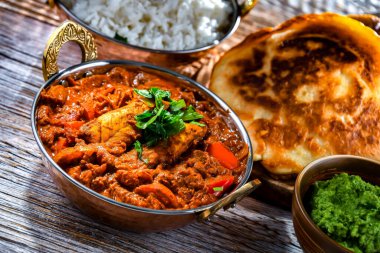 Pirinçli tereyağlı tavuk ve Hint karahi kaplarında servis edilen mısır ekmeği..