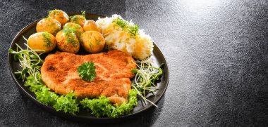 Patates ve lahana ile servis edilen ekmek kırıntılarıyla kaplı domuz pirzolası.