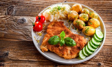 Patates ve lahana ile servis edilen ekmek kırıntılarıyla kaplı domuz pirzolası.