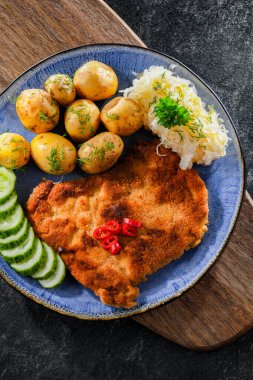 Patates ve lahana ile servis edilen ekmek kırıntılarıyla kaplı domuz pirzolası.