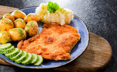 Patates ve lahana ile servis edilen ekmek kırıntılarıyla kaplı domuz pirzolası.