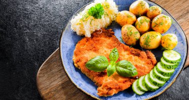 Patates ve lahana ile servis edilen ekmek kırıntılarıyla kaplı domuz pirzolası.