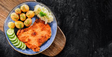 Patates ve lahana ile servis edilen ekmek kırıntılarıyla kaplı domuz pirzolası.