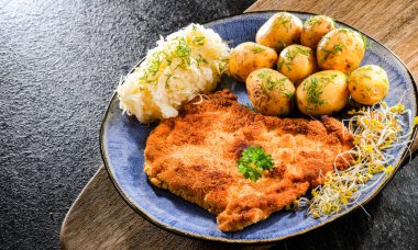 Patates ve lahana ile servis edilen ekmek kırıntılarıyla kaplı domuz pirzolası.