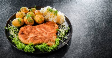 Patates ve lahana ile servis edilen ekmek kırıntılarıyla kaplı domuz pirzolası.