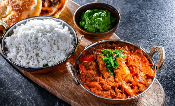 Butter chicken with rice and naan flatbread served in original indian karahi pots.