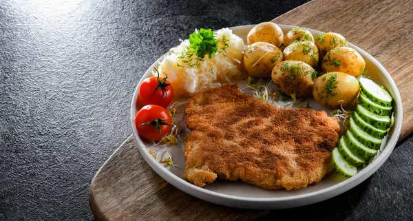 Patates ve lahana ile servis edilen ekmek kırıntılarıyla kaplı domuz pirzolası.