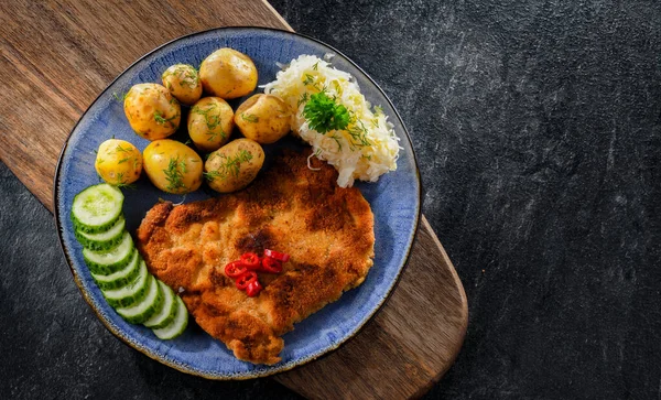 Pork breaded cutlet coated with breadcrumbs served with potatoes and cabbage