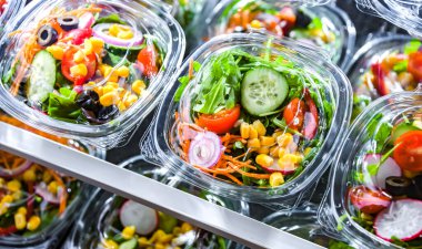 Önceden paketlenmiş sebze salatalarıyla dolu plastik kutular. Ticari bir buzdolabında satılıyor.