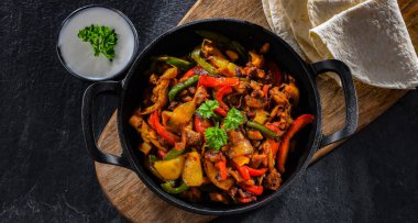 Fajita biberli ve soğanlı sıcak demir tavada servis ediliyor.