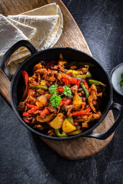 Fajita biberli ve soğanlı sıcak demir tavada servis ediliyor.