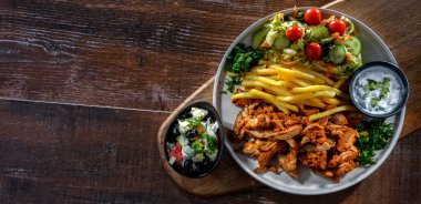 Kebab served with french fries, vegetable salad and tzatziki
